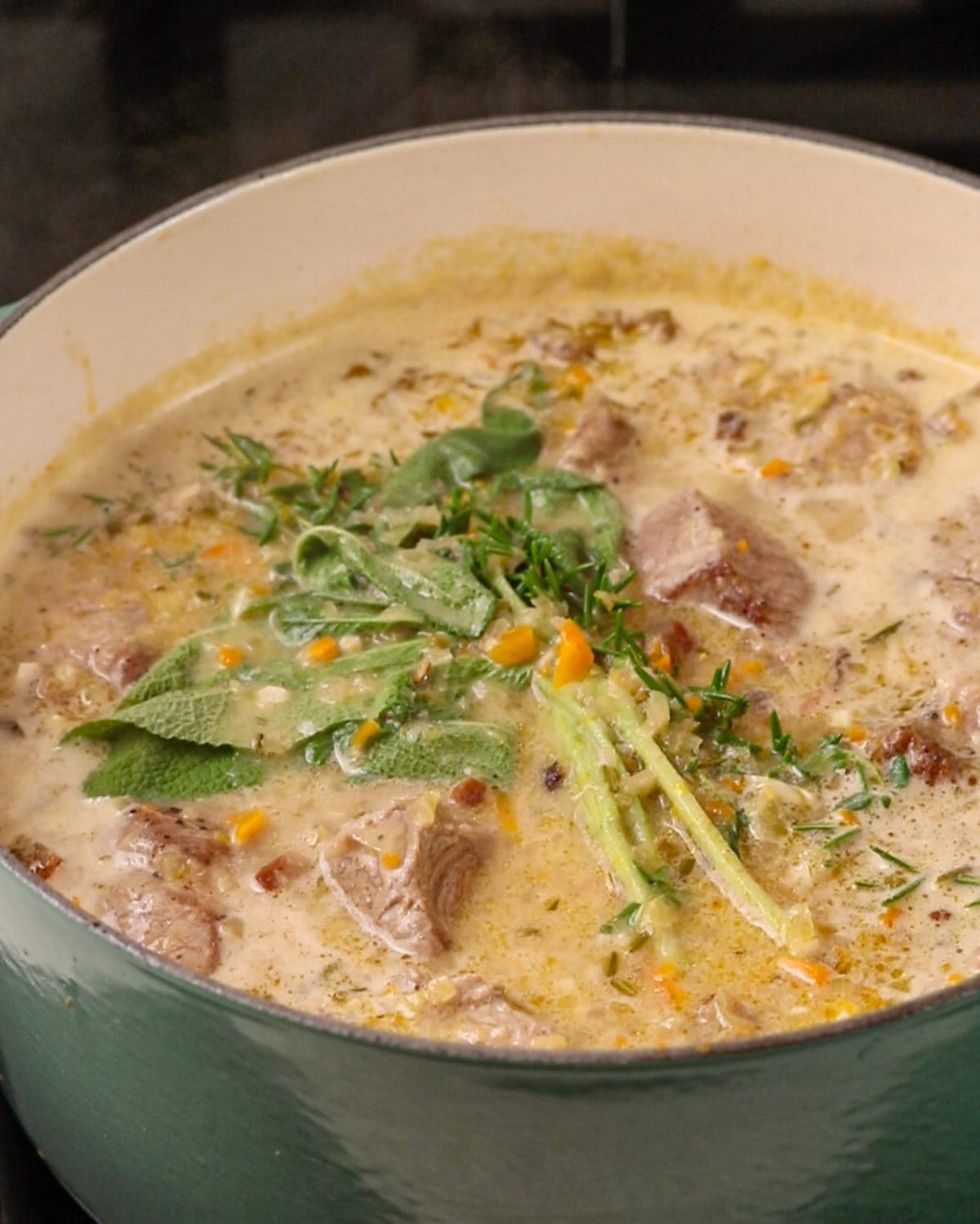 Liquids added into pot with a bunch of herbs tied together sitting on top.