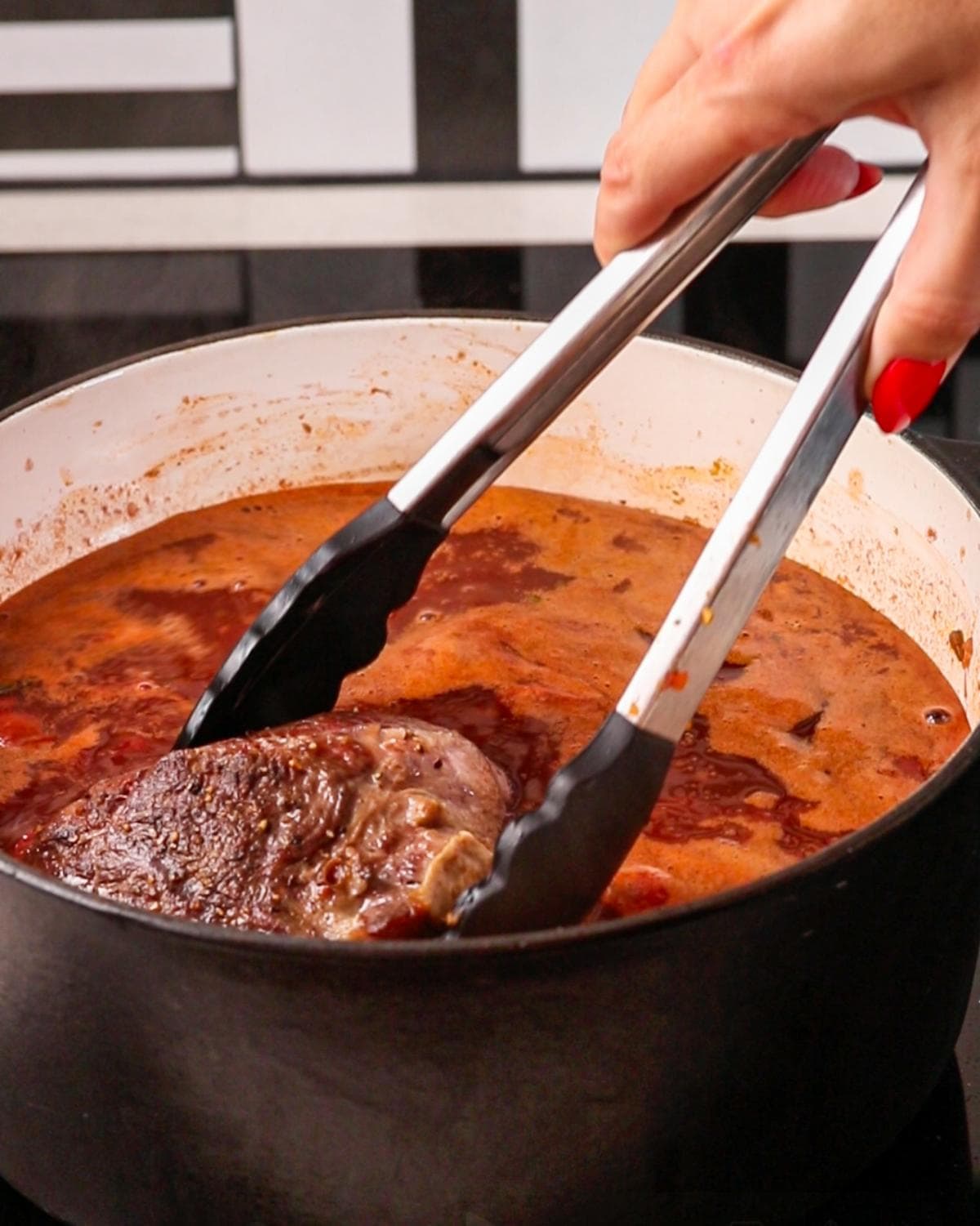 Browned beef cheeks returned to the braising liquid before slow cooking.