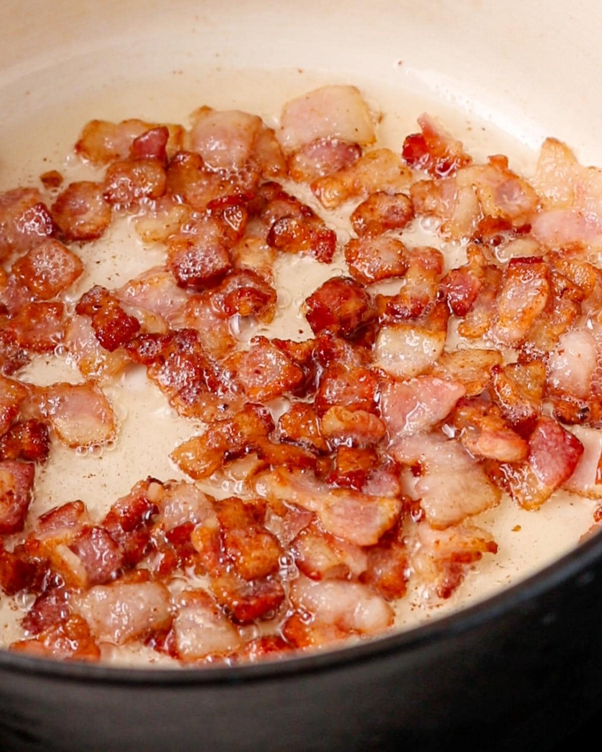 Pancetta cooking until golden in a Dutch oven.