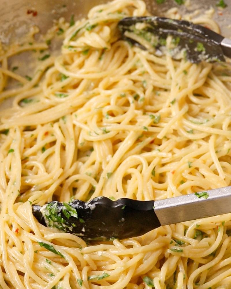 Tonga tossing parsley through the spaghetti.