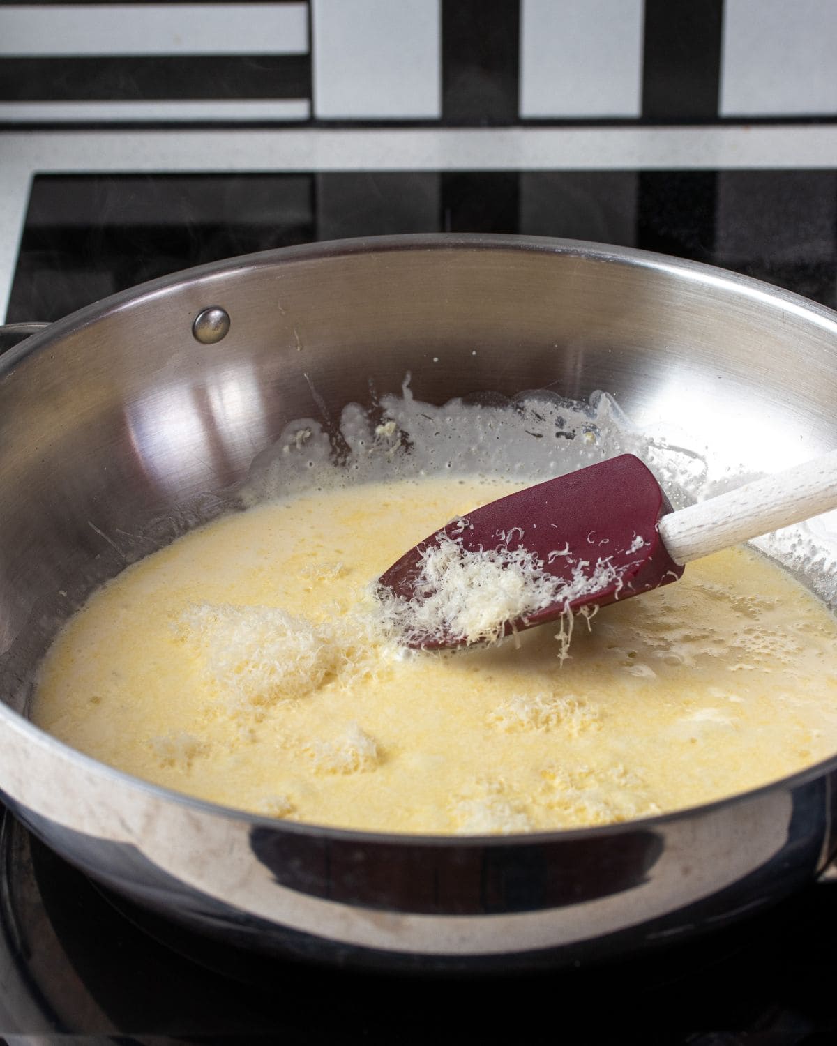Finely grated parmesan being stirred into a creamy sauce