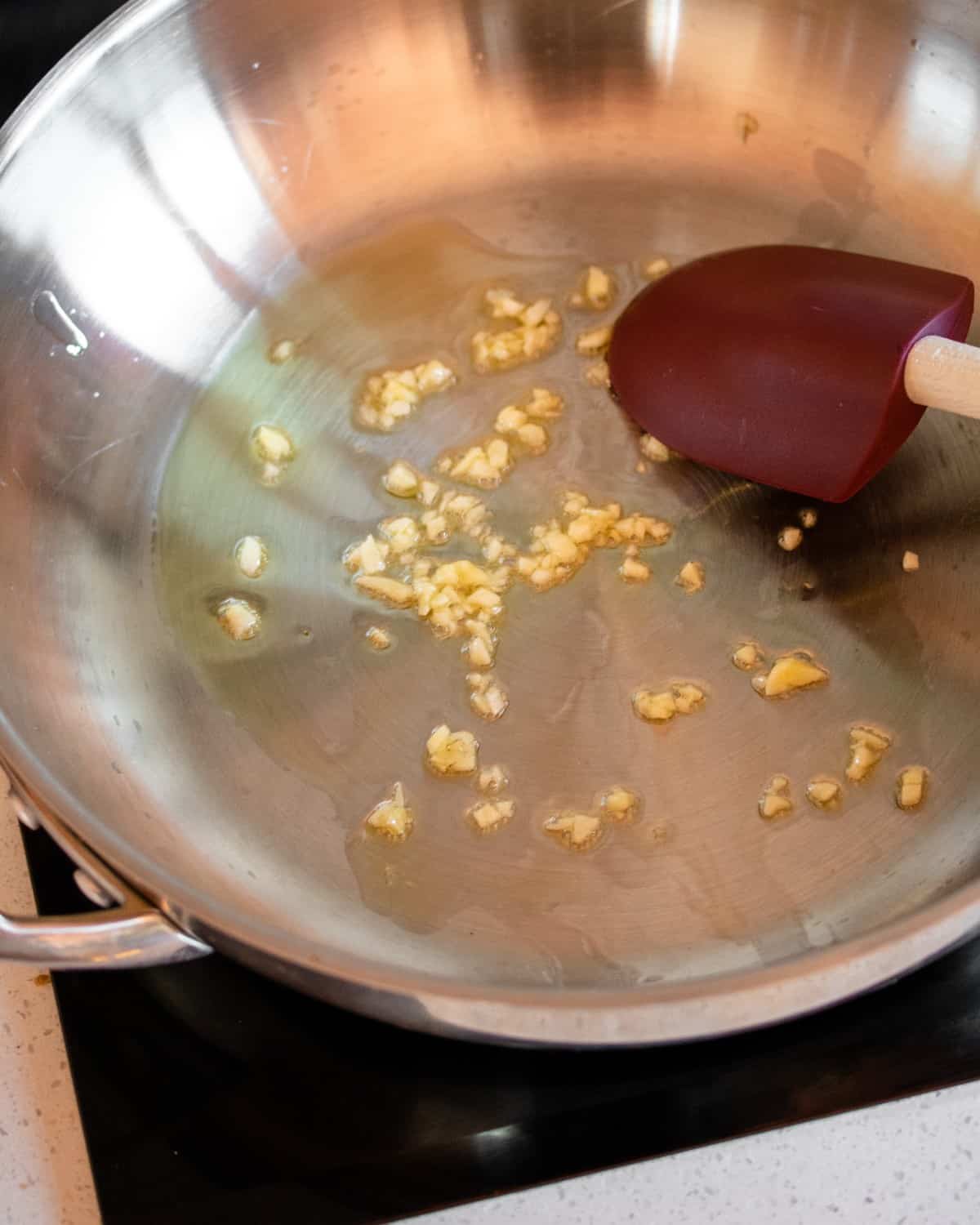 Stainless steel fry pan with garlic sizzling.