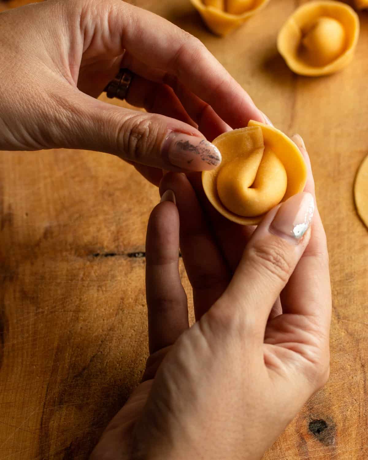 Hands holding the finished cappelletti.