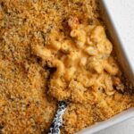 Mac and cheese in a rectangle porcelain dish. Spoon is digging in.
