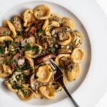 Creamy mushroom pasta on a white plate with a fork resting in.