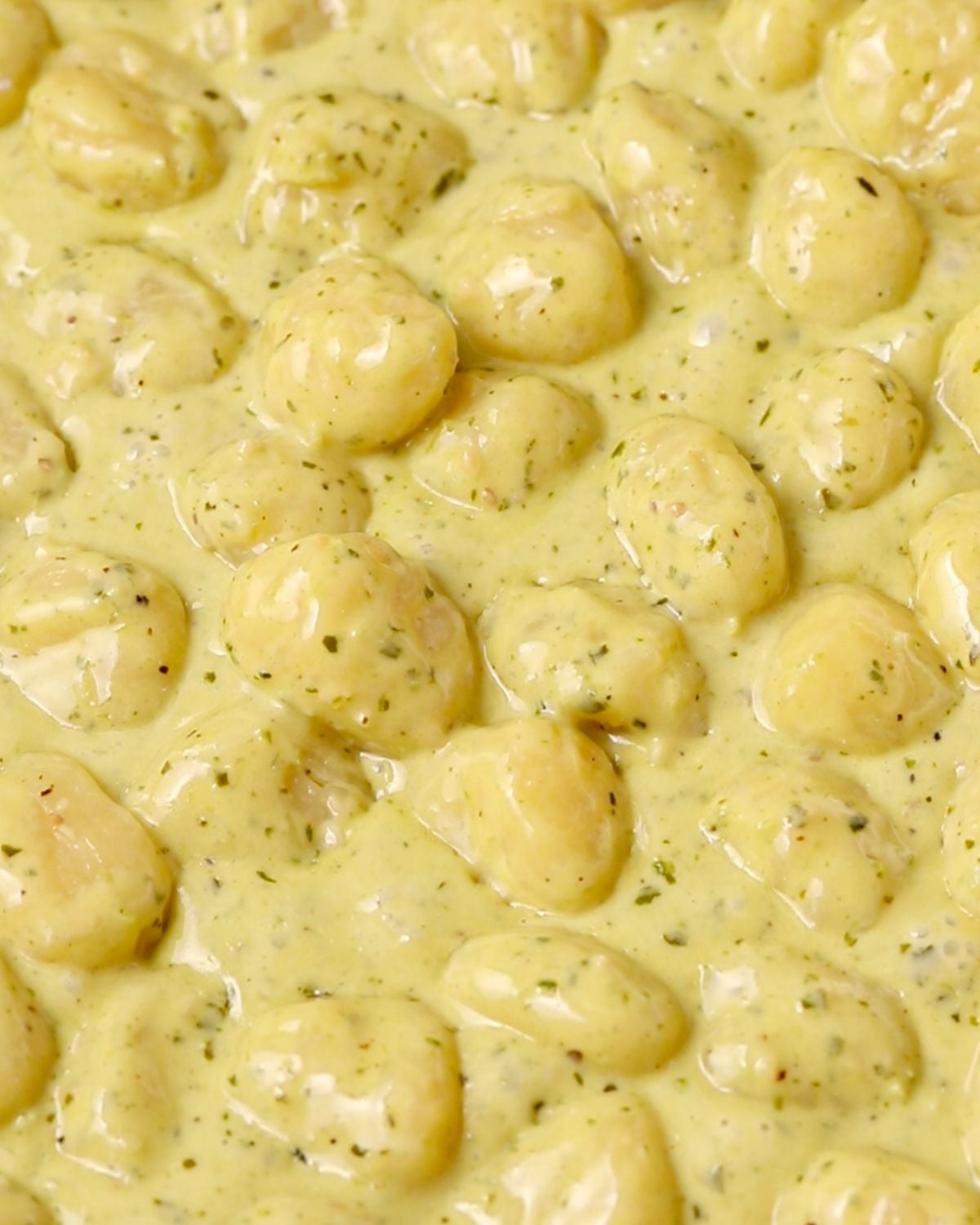 Cooked gnocchi simmering in the creamy pesto sauce.