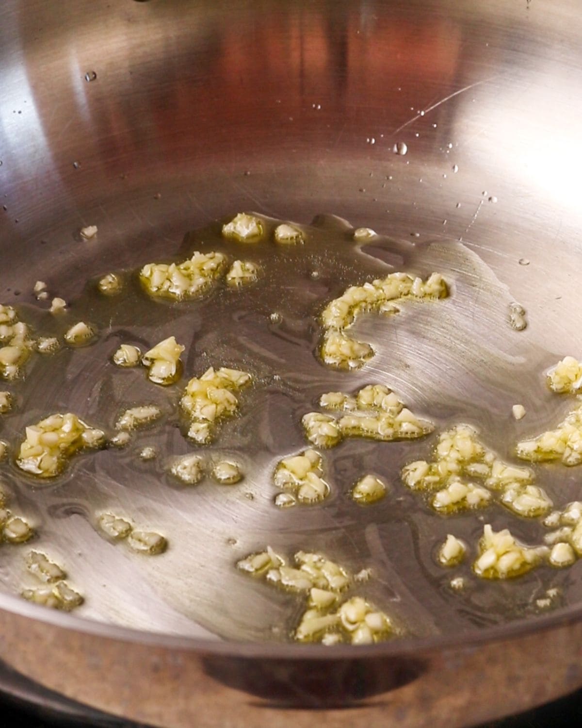 Minced garlic sizzling in a stainless steel pan.