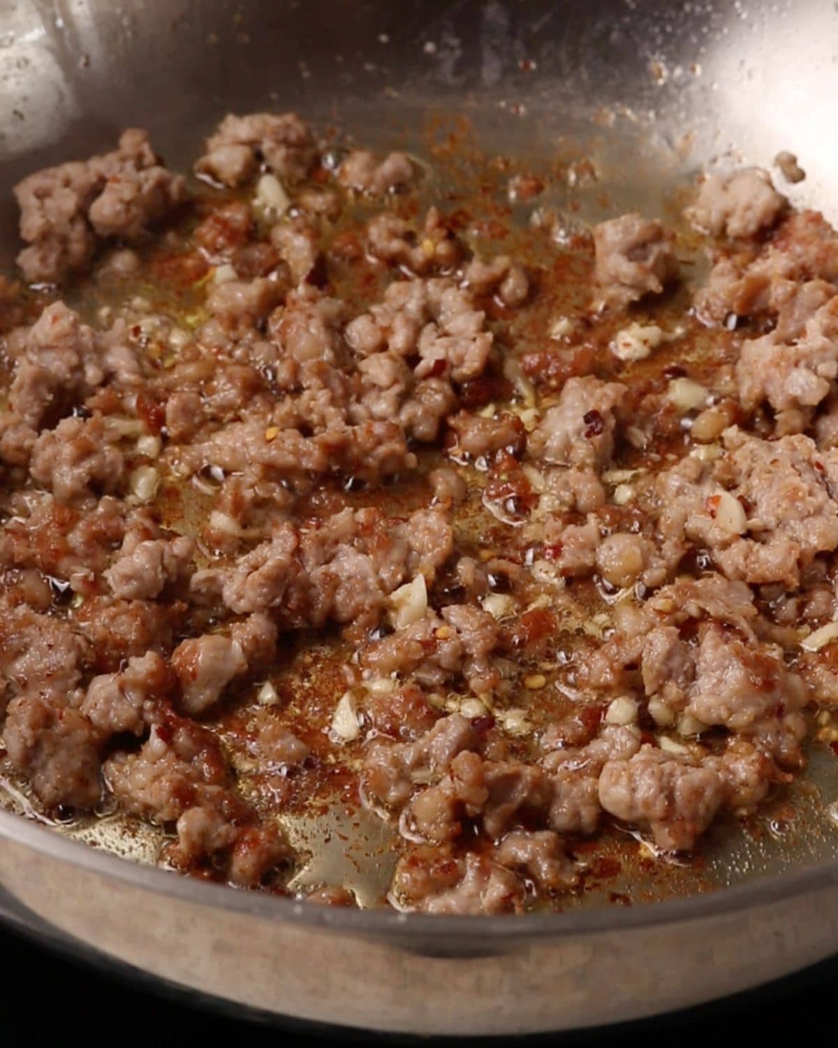 Sausage meat frying in a skillet.