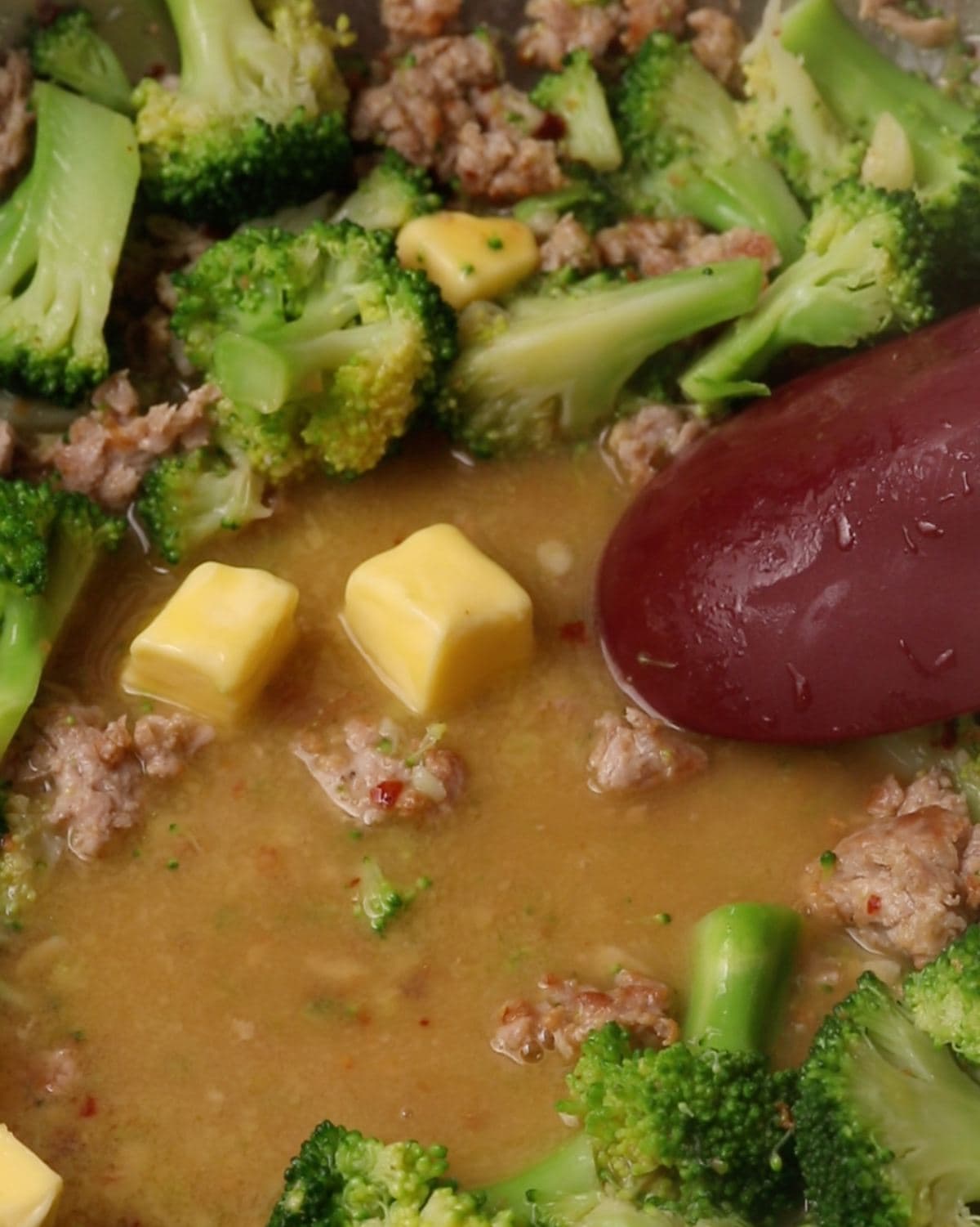 Cubes of butter melting into the broccoli and sausage mixture.