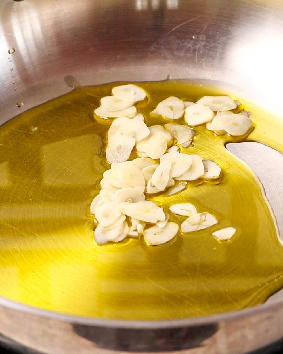 Sliced garlic and olive oil in a pan.