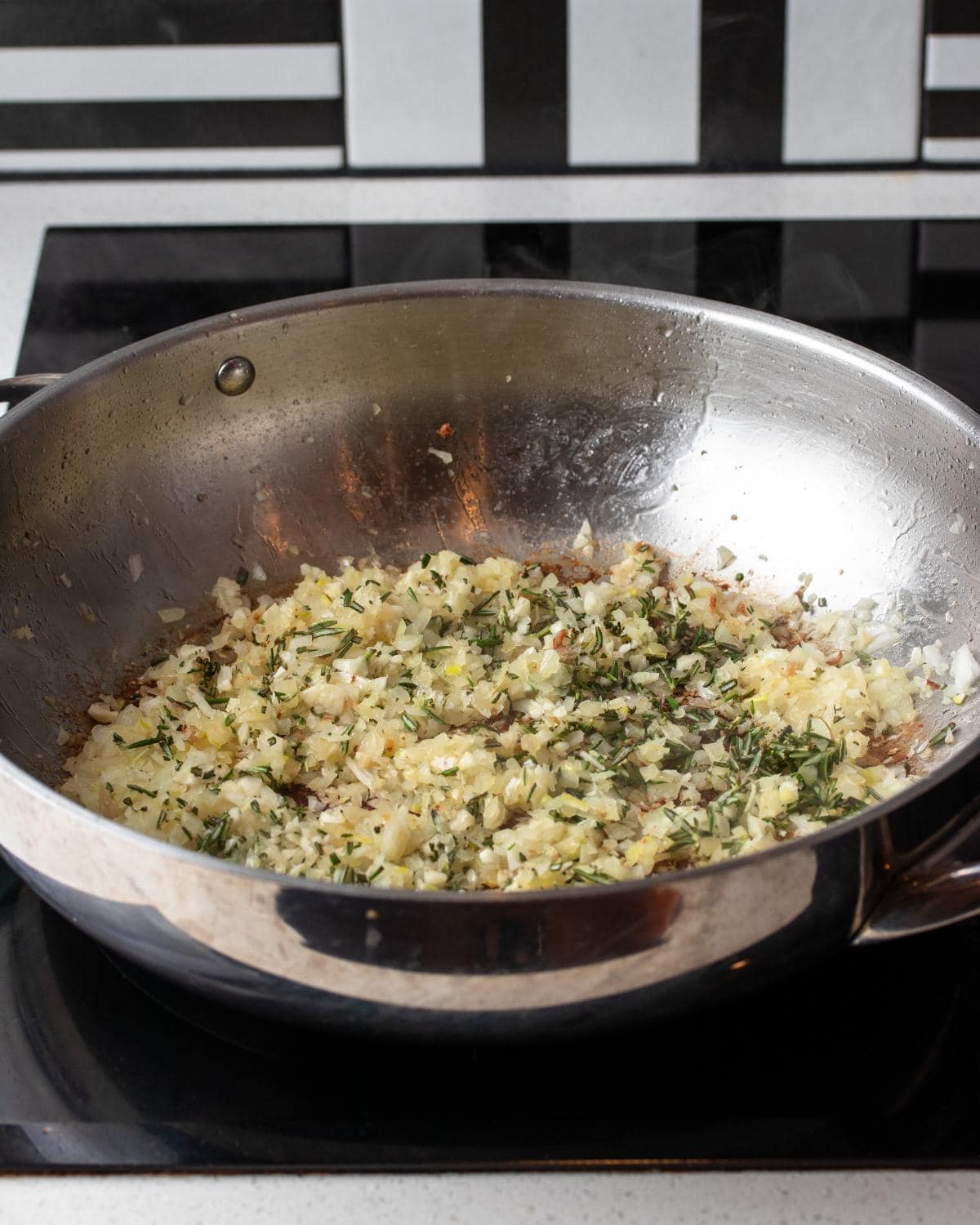 Diced onion, garlic and rosemary in a stainless steel pan. 