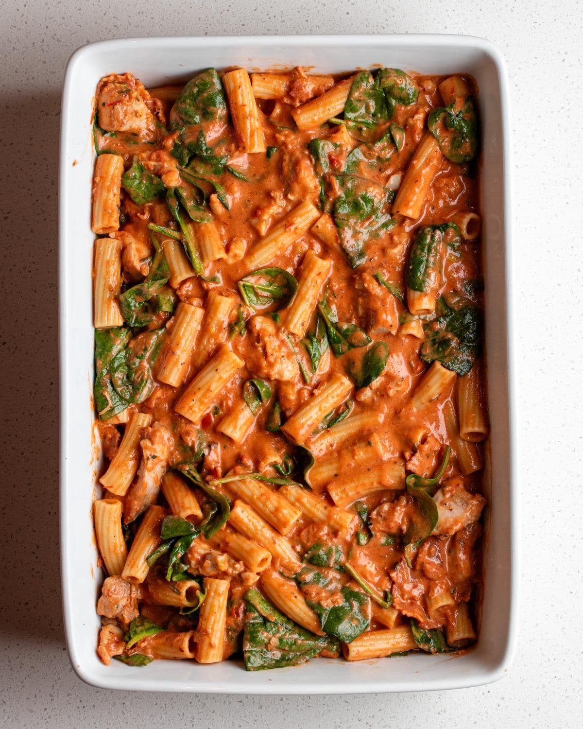 Pasta mixture spread out into a rectangle white porcelain dish.