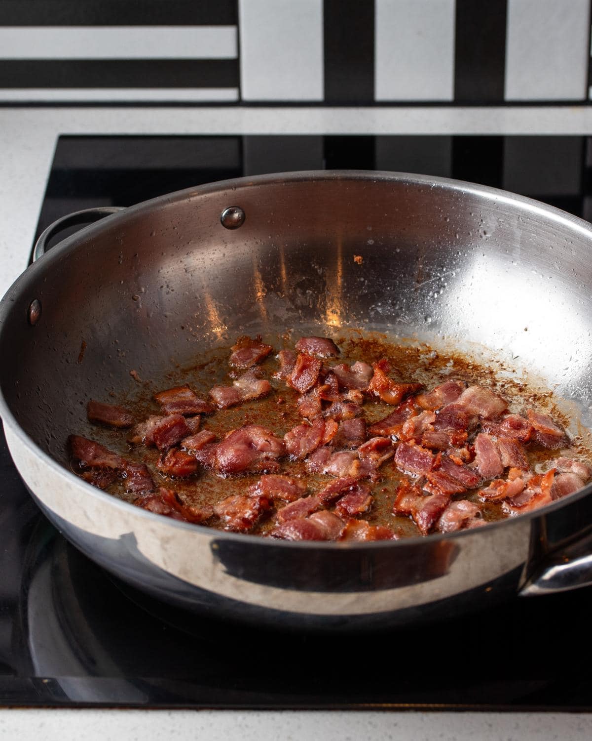 Bacon sizzling in a stainless steel pan.