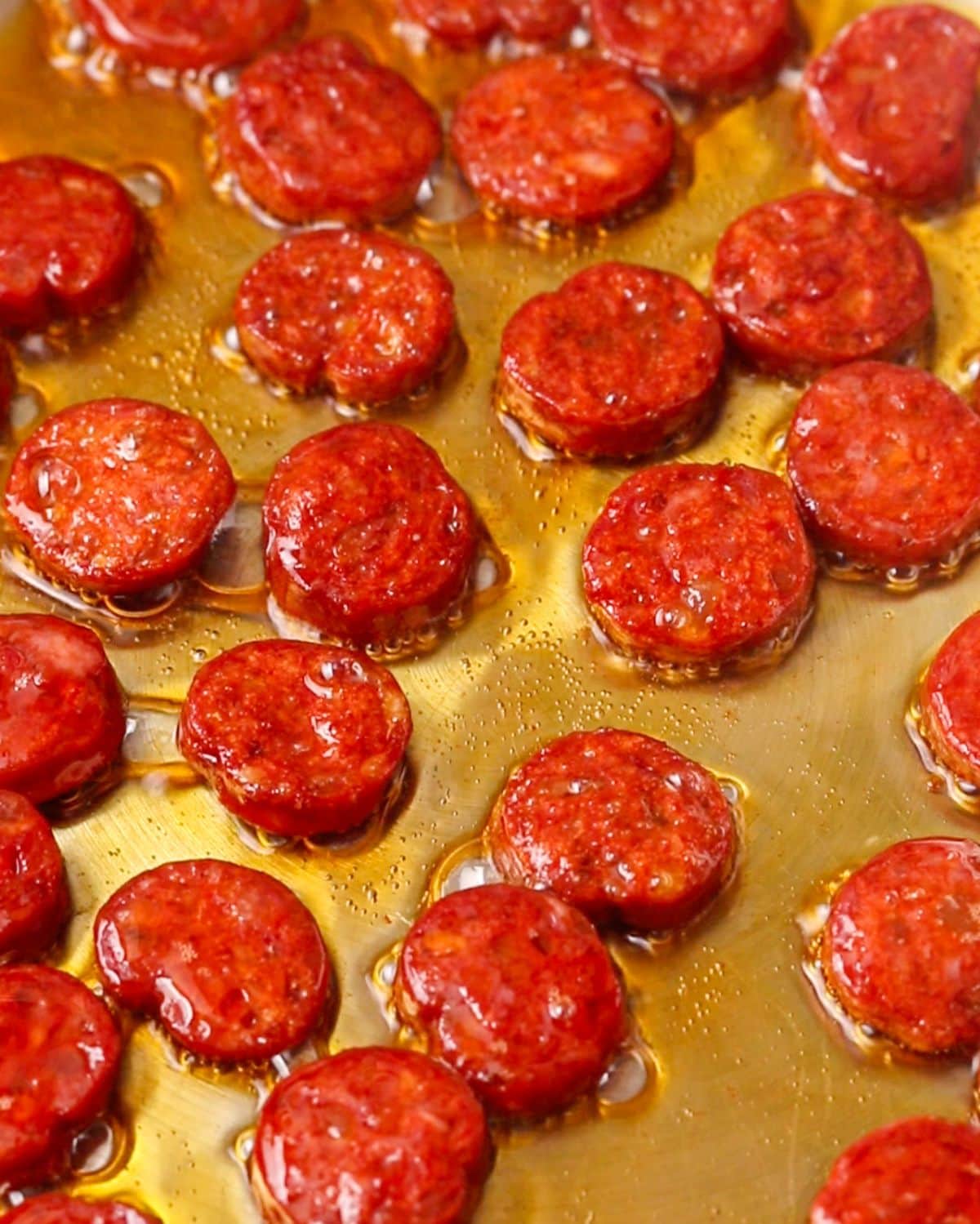 Sliced chorizo sausage sizzling in a pan.