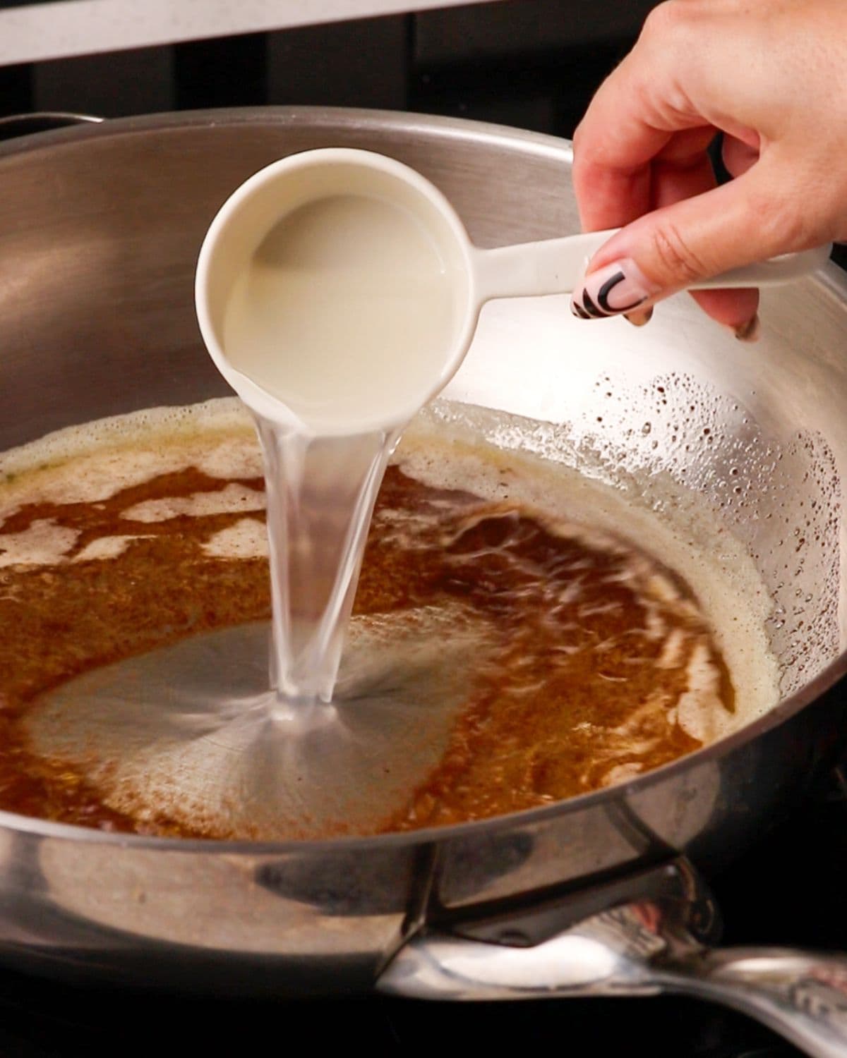 Pasta water being poured into the brown butter.