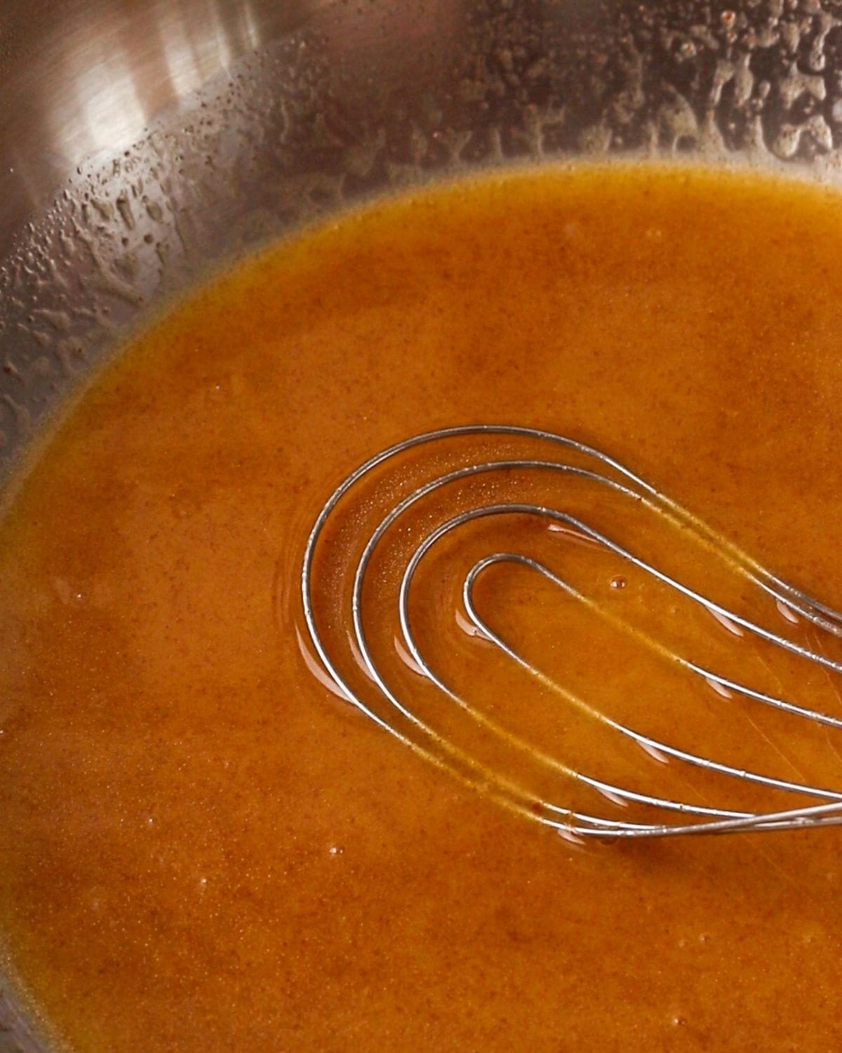 A flat whisk laying down into the butter mixture.