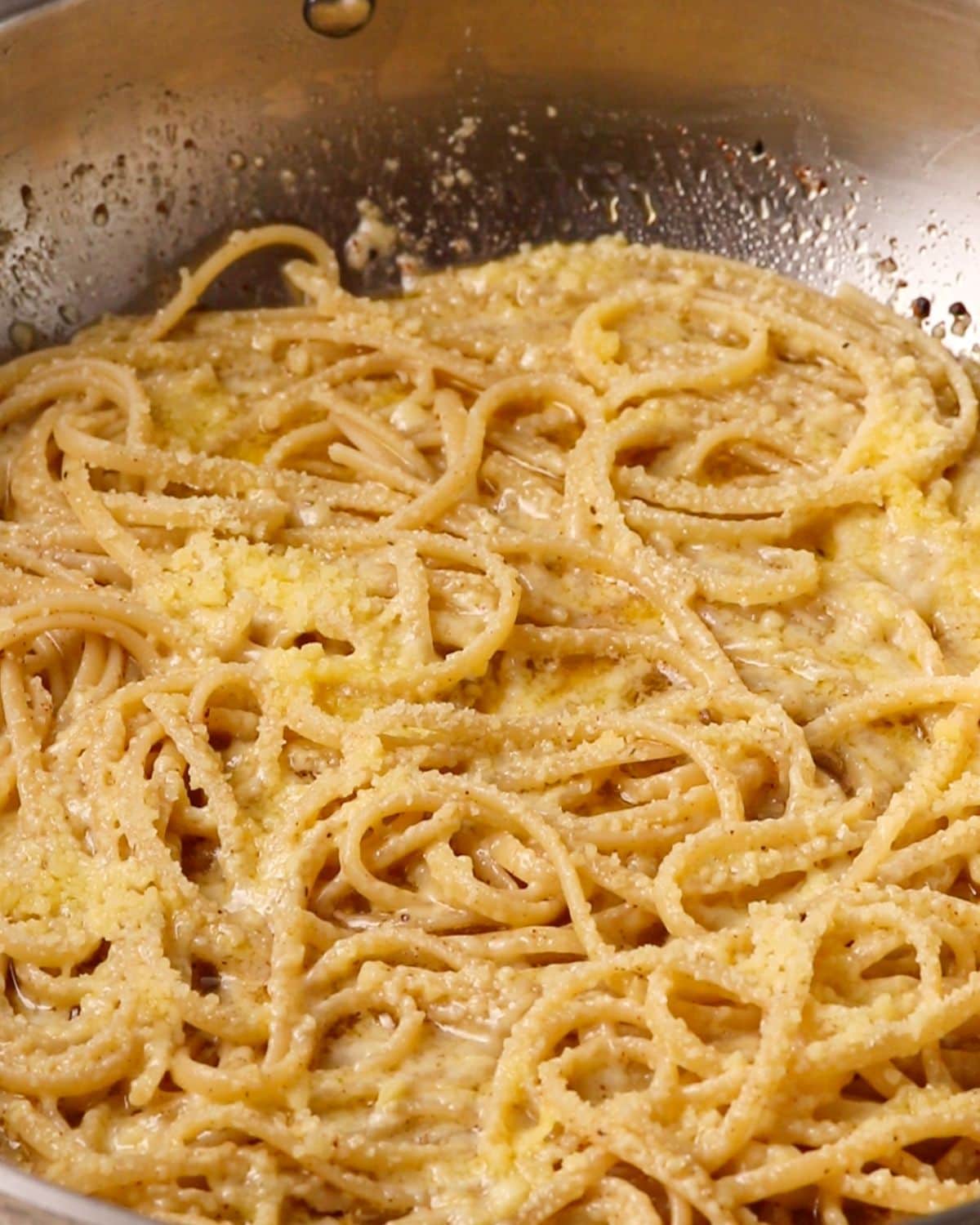 Pasta with melted parmesan on top in the pan.