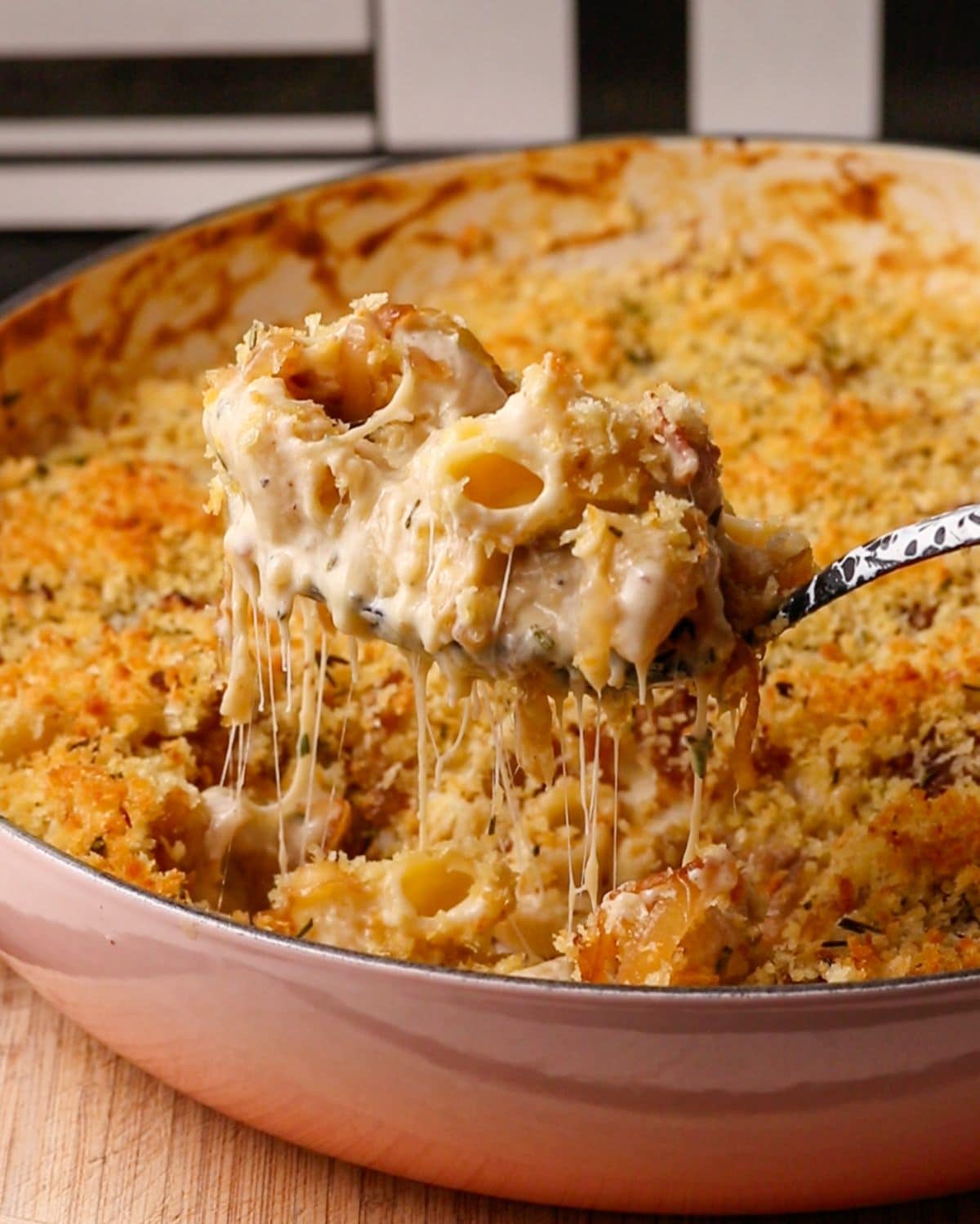 A spoon lifting up some mac and cheese with strings of cheese pulling.