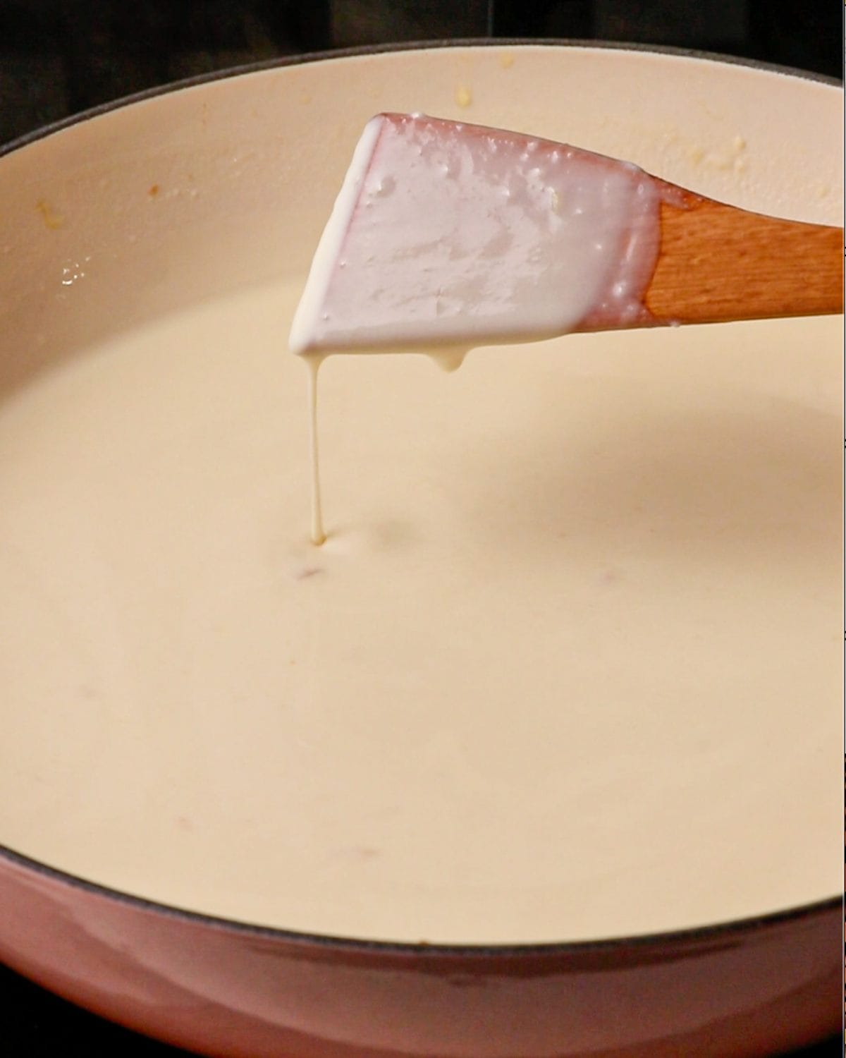 A wooden spoon coated with the bechamel sauce.