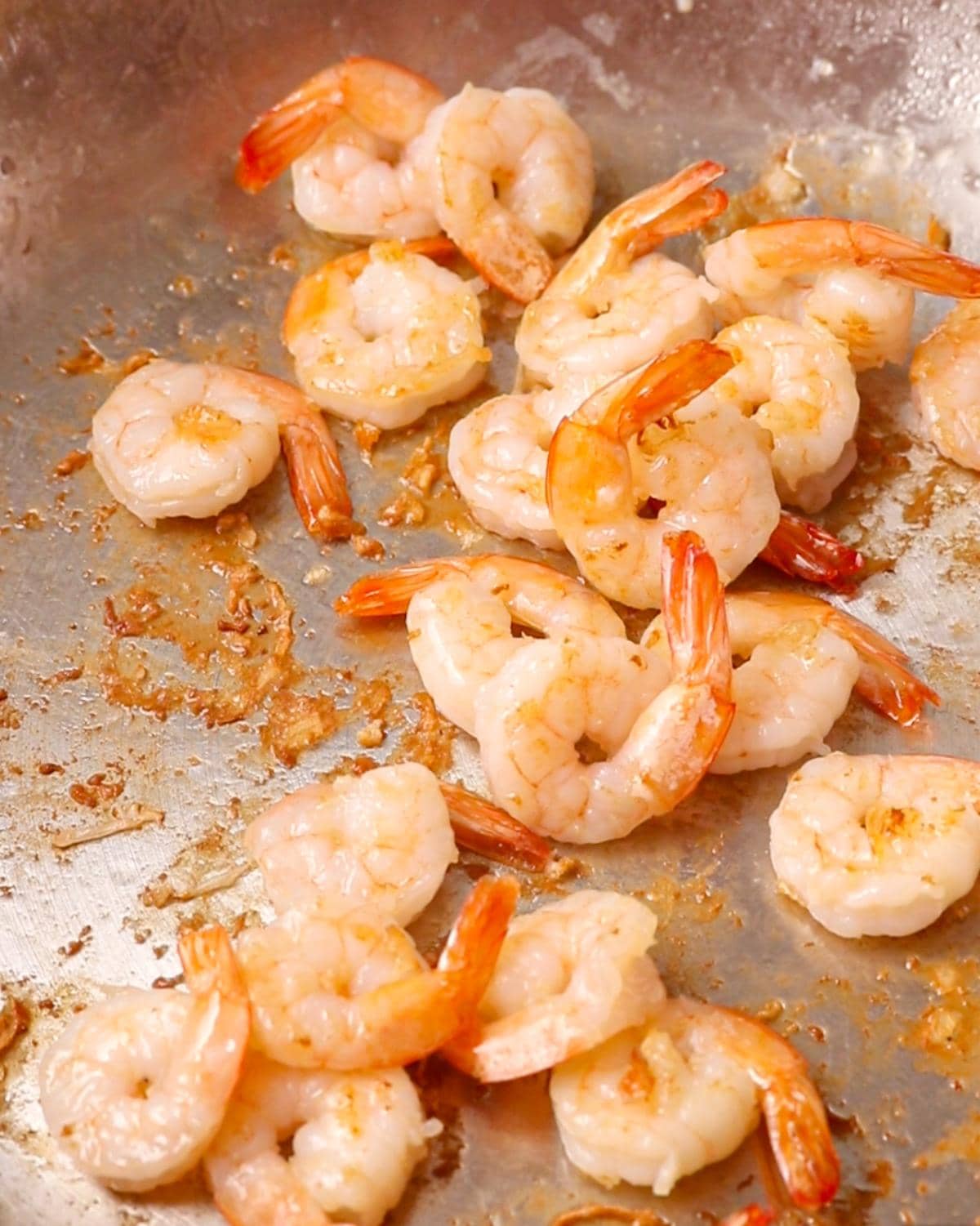 Shrimp pan frying in a stainless steel pan.