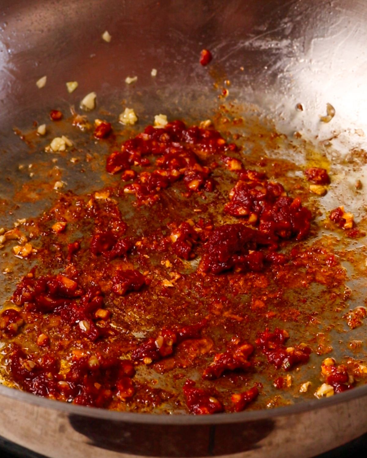 Minced garlic and tomato paste mixed in the pan.