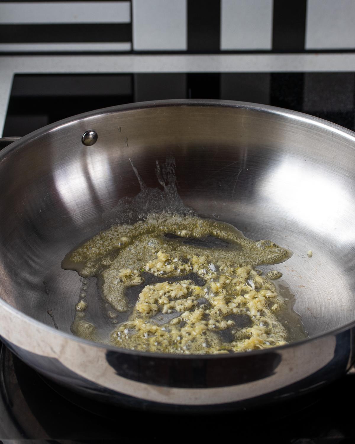 Chopped garlic and butter sizzling in a stainless steel fry pan.