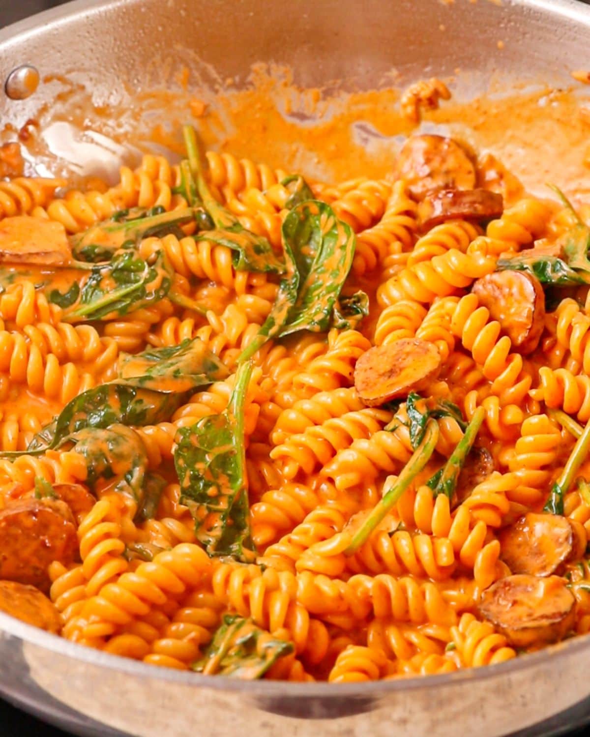 Cooked fusilli pasta and spinach mixed through the sauce.