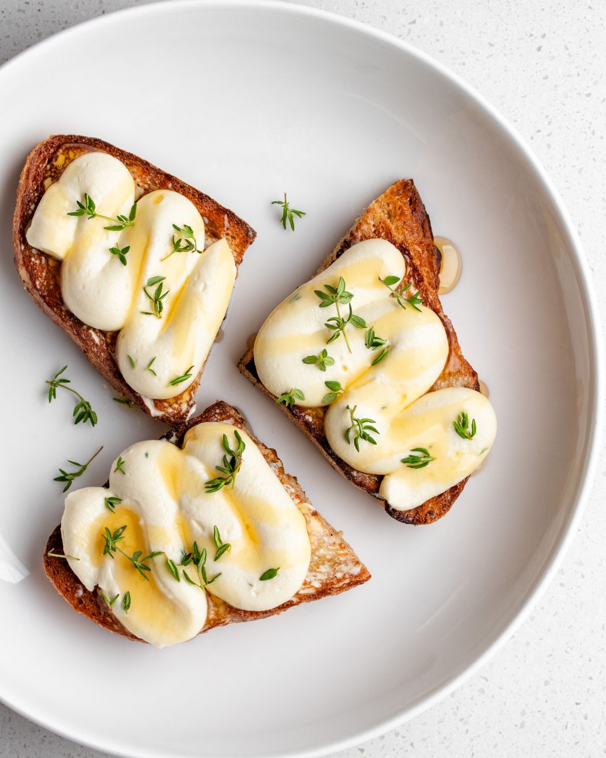 Golden toasted sourdough with piped whipped ricotta on top. Drizzled with honey and thyme leaves.
