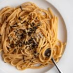 White plate with spaghetti in a miso butter sauce. Furikake sprinkled on top.