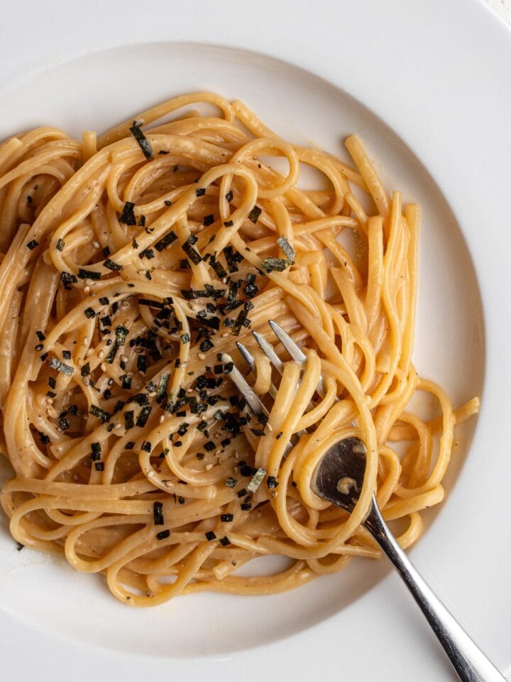 White plate with spaghetti in a miso butter sauce. Furikake sprinkled on top.
