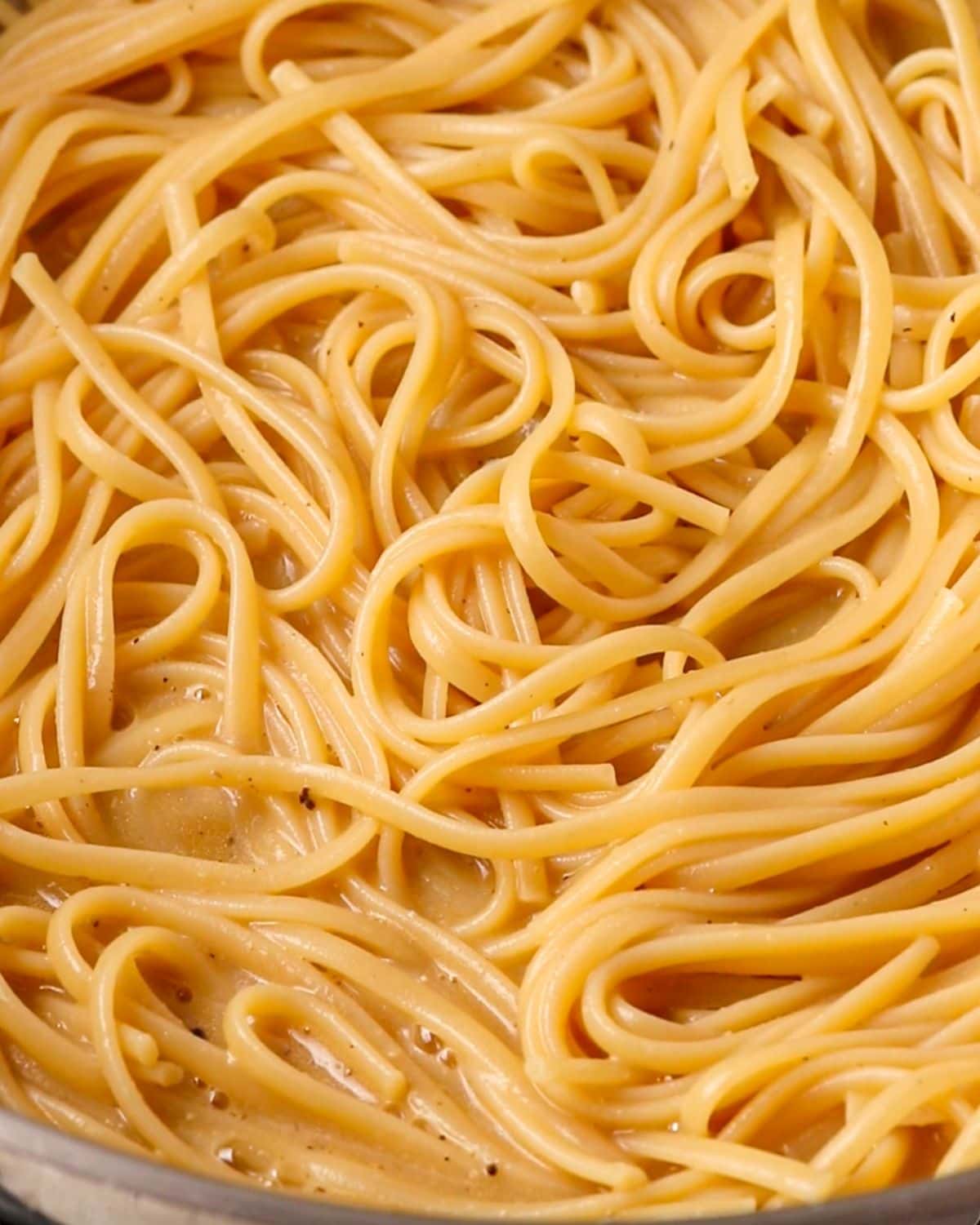 Cooked pasta tossed with the butter sauce in the pan.