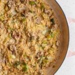 Creamy orzo with sausage pieces and leeks mixed through. In a round casserole pot.