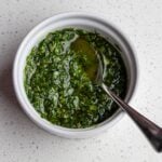 A white ramekin with gremolata and a teaspoon resting in.