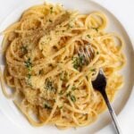 White plate with linguine in a garlic butter sauce. Fork resting in with noodles wrapped around