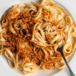 White plate with linguine in a creamy sauce and toasted panko pangrattato on top.