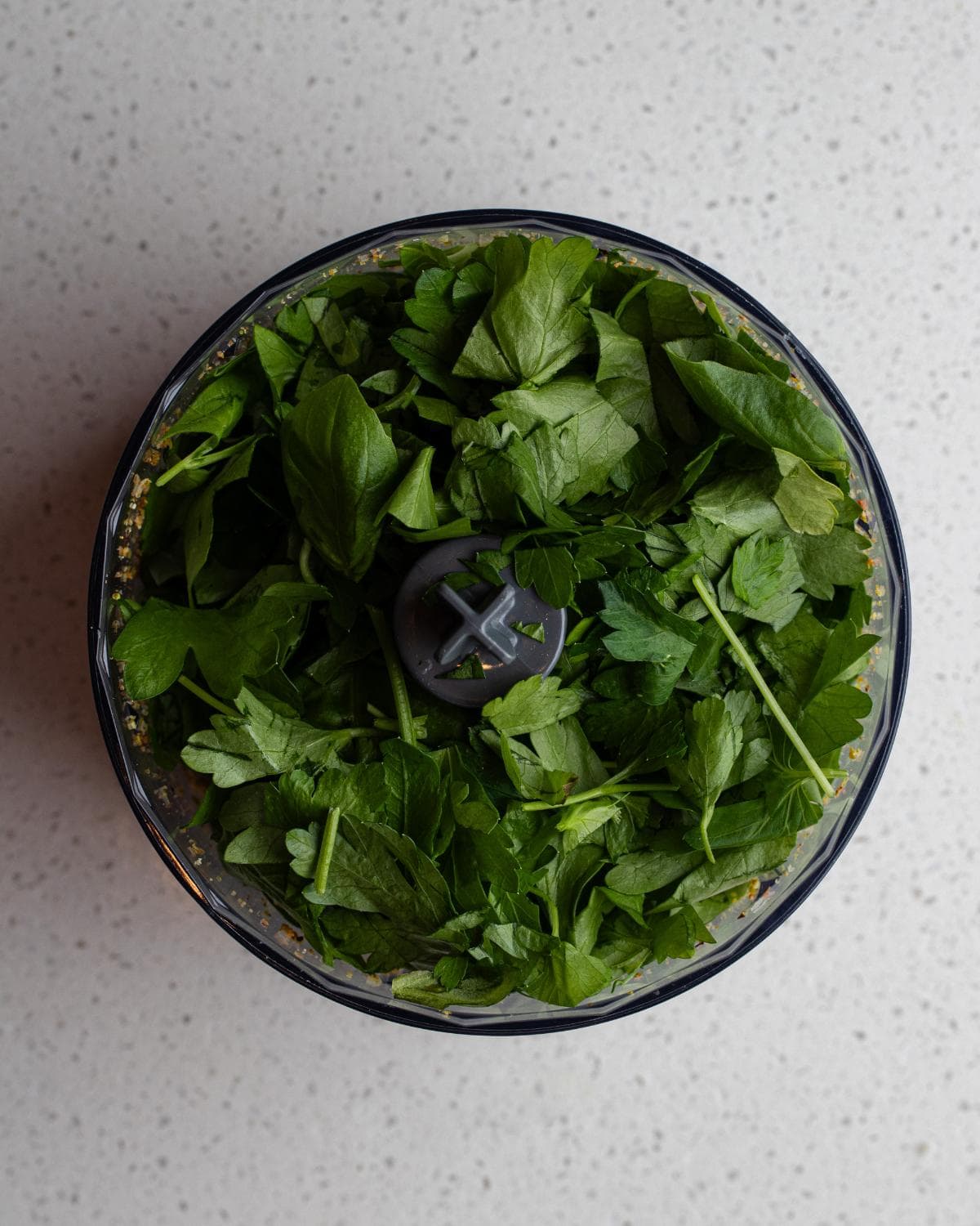 Basil and parsley added to processor.