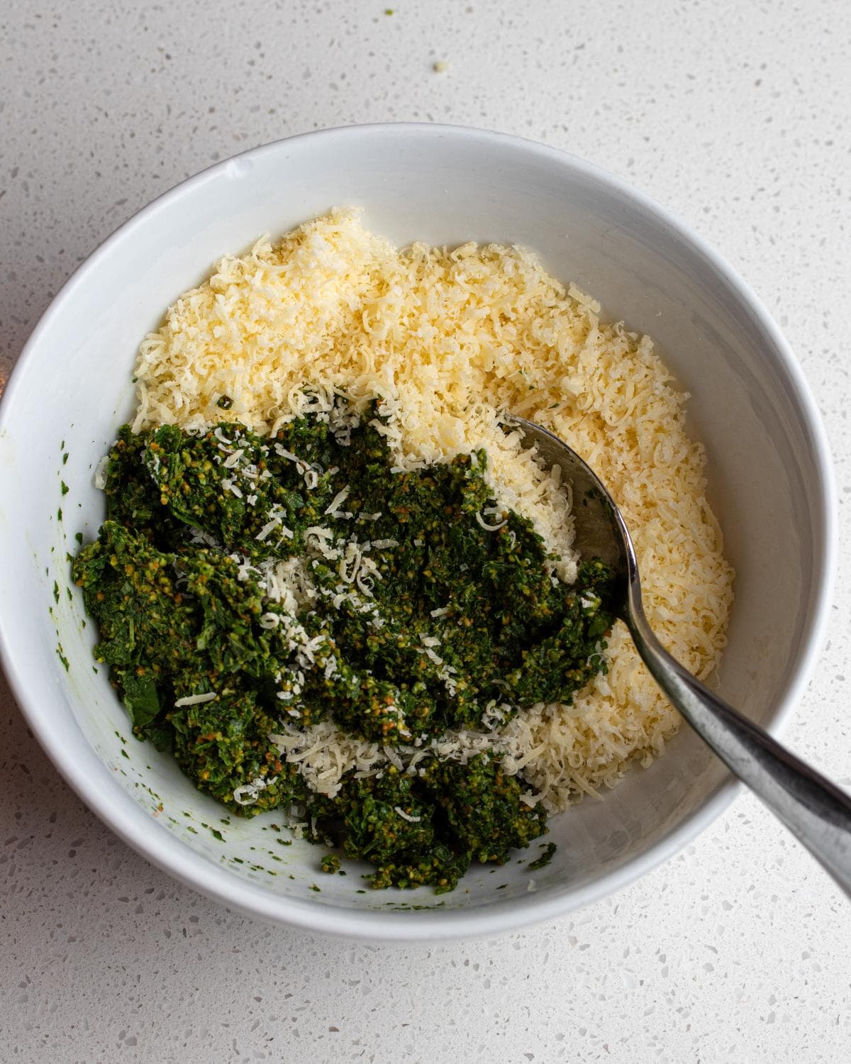 Pesto mixture with grated parmesan in bowl.