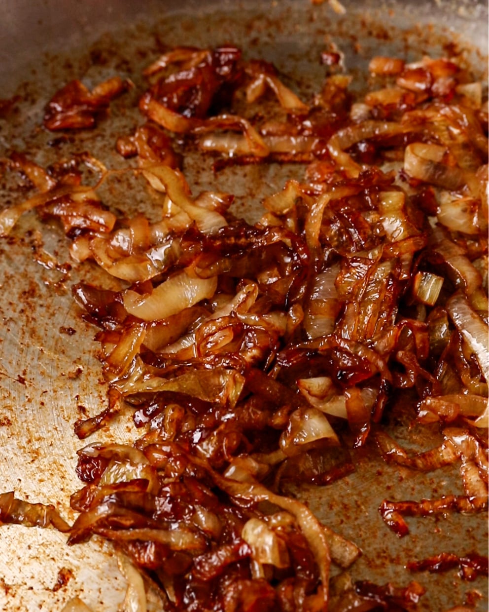 Caramelized onions cooked until deeply golden and soft in a pan.