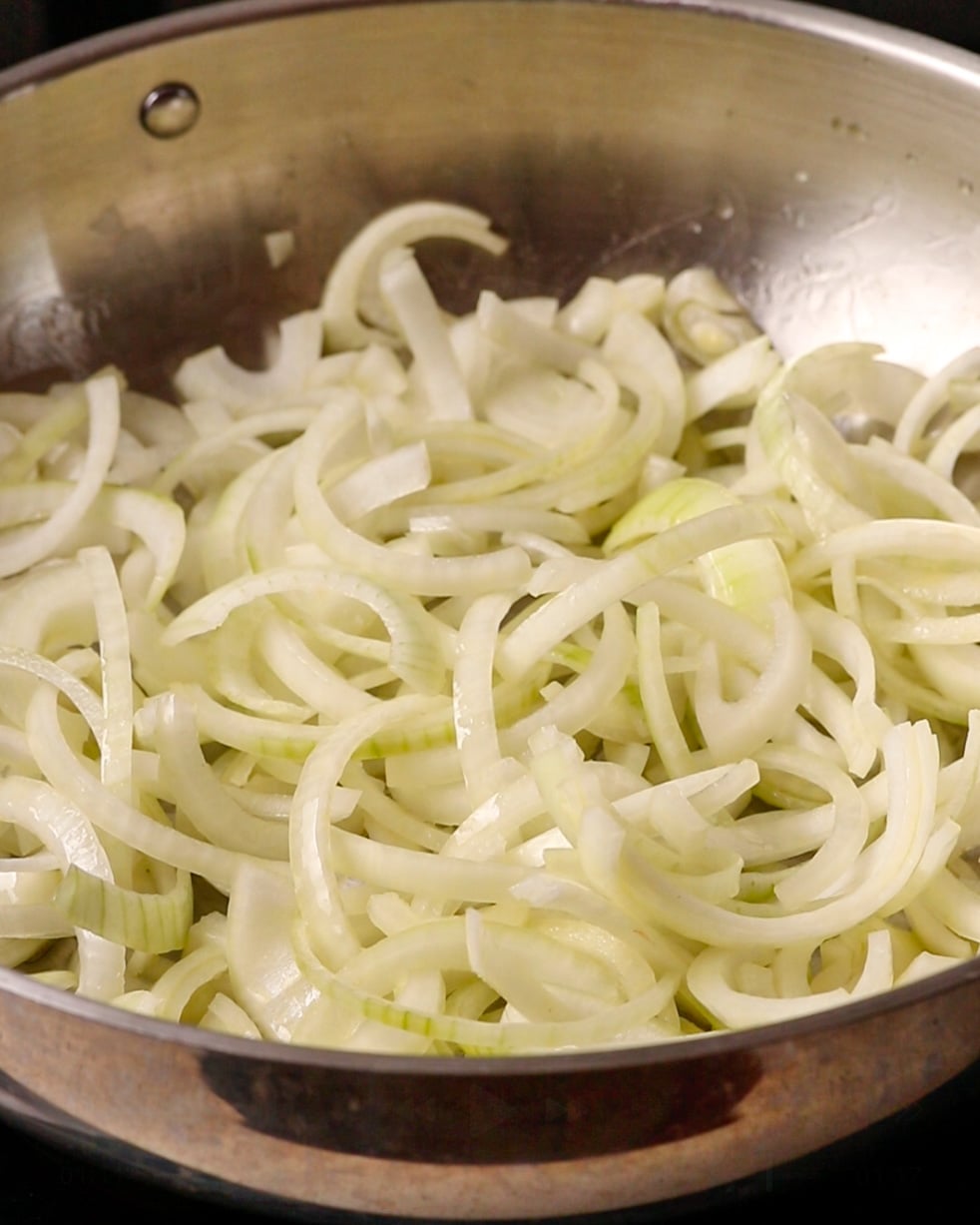 Sliced onions cooking in butter and olive oil in a pan.