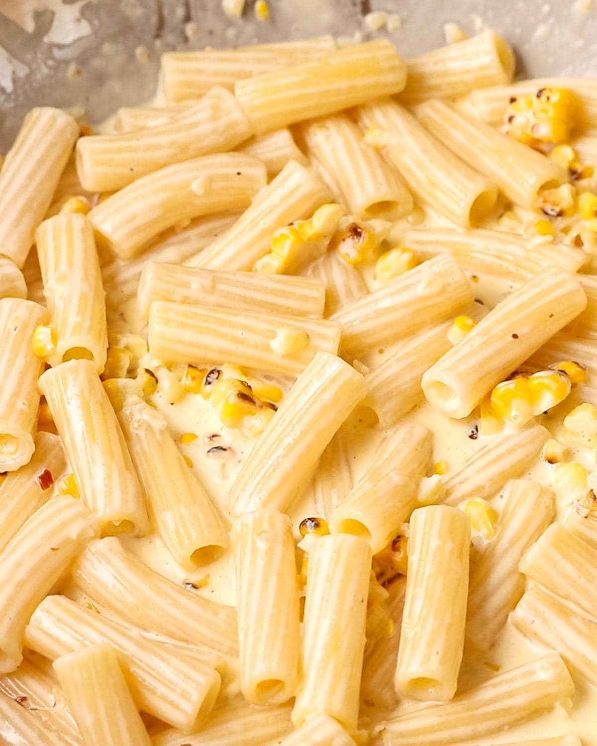 Creamy corn pasta coated in a silky parmesan sauce in a pan.