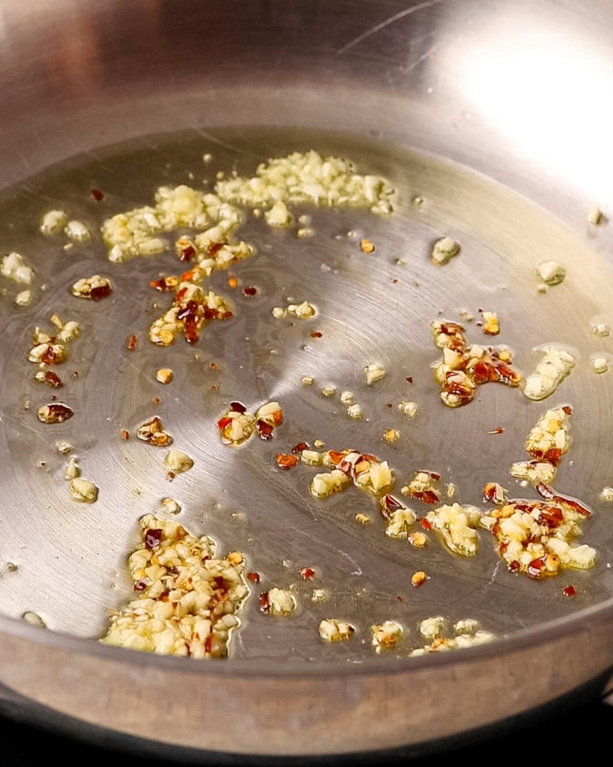 Garlic and red pepper flakes gently cooking in butter in a pan.