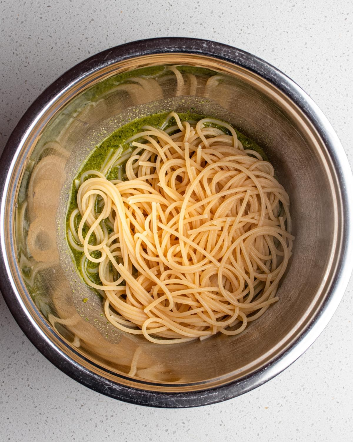 Cooked pasta added to the bowl with pesto sauce.