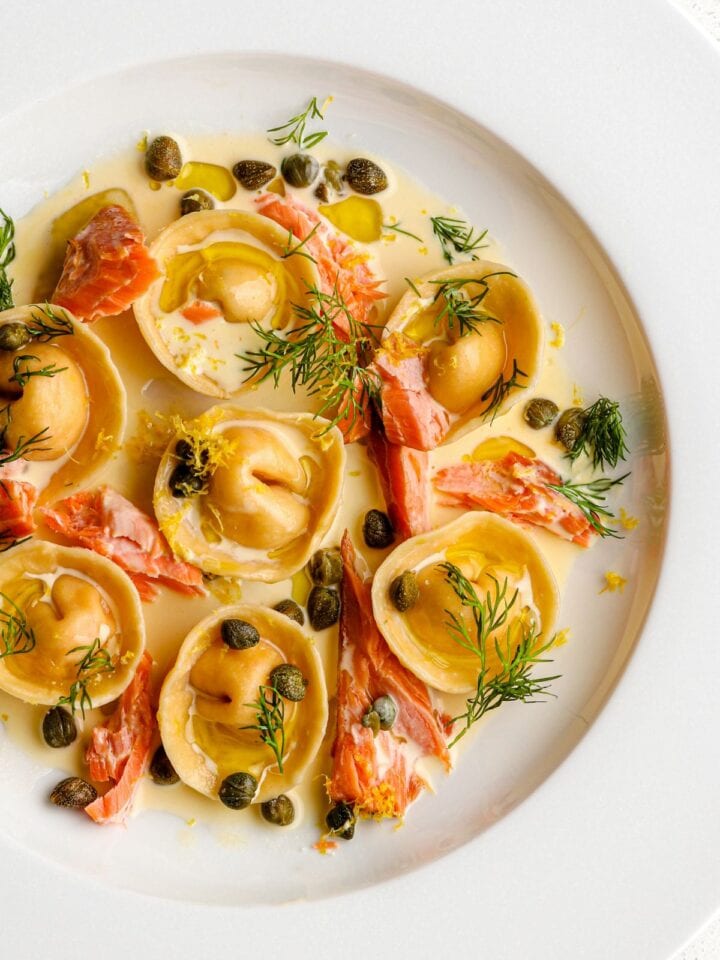 Salmon ravioli in a cream sauce with flaked hot smoked salmon and fresh dill on top.