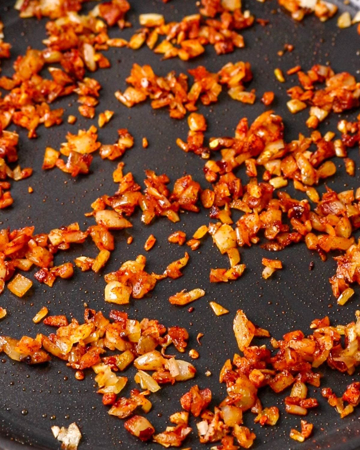Onion, garlic, chili flakes and smoked paprika cooking in bacon fat.