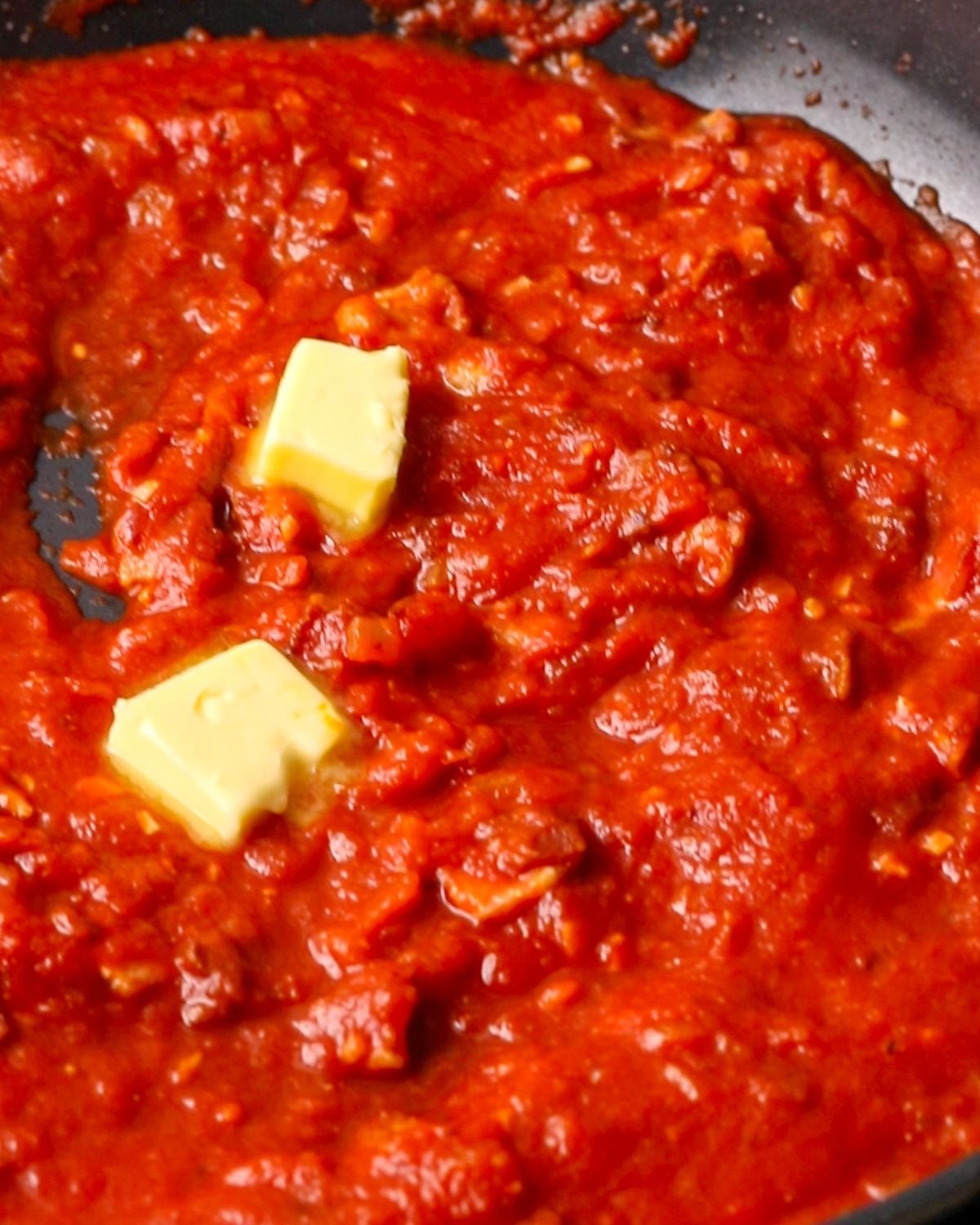 Butter melting into the tomato bacon   sauce in skillet.