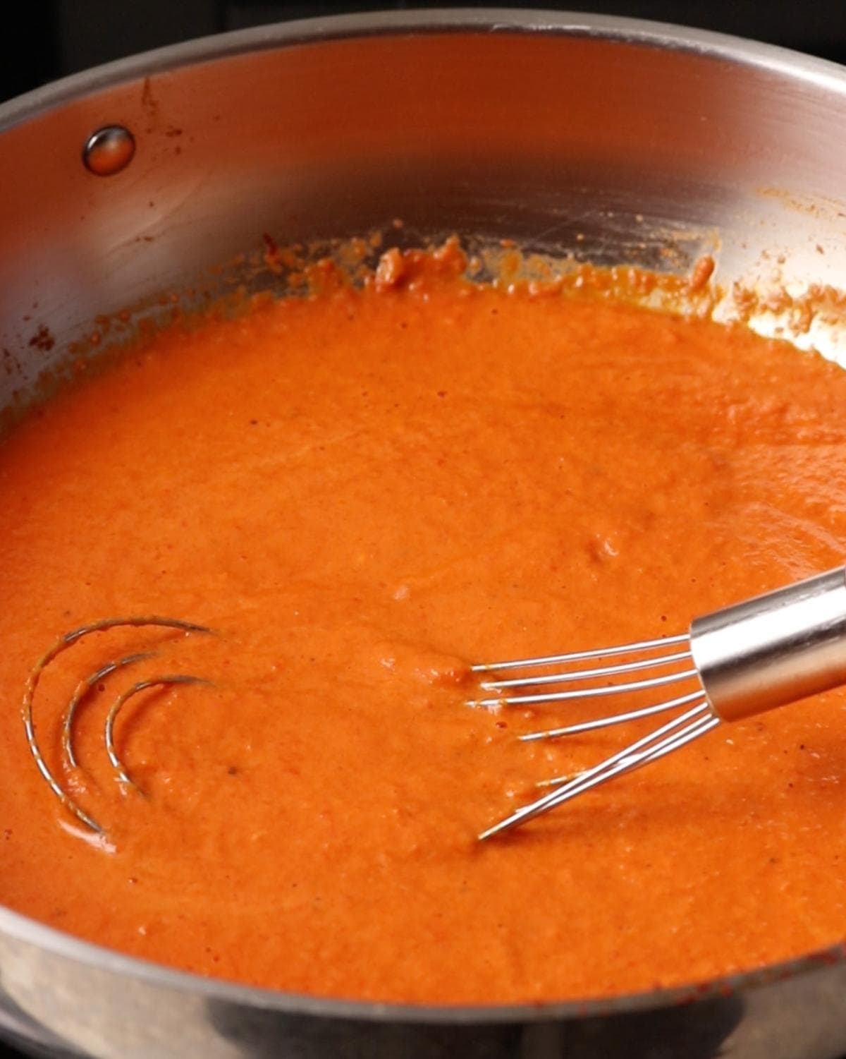 Blended roasted red pepper sauce simmering in a skillet.