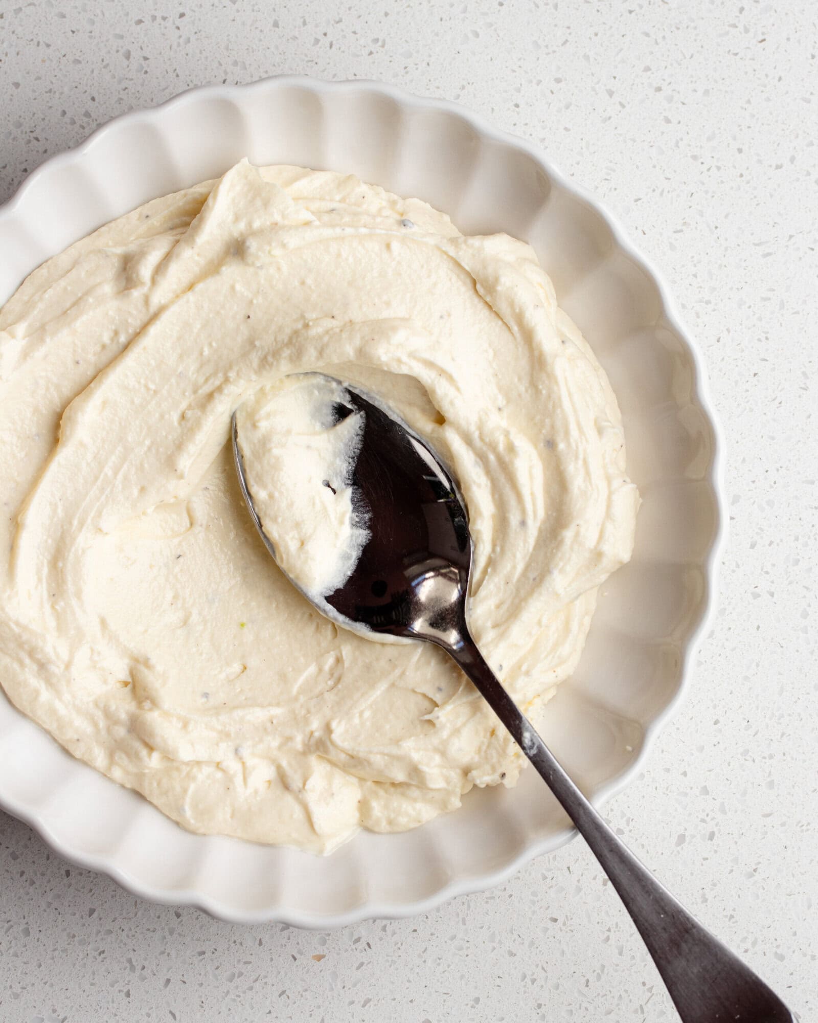 Whipped feta in a white bowl with a spoon resting in.