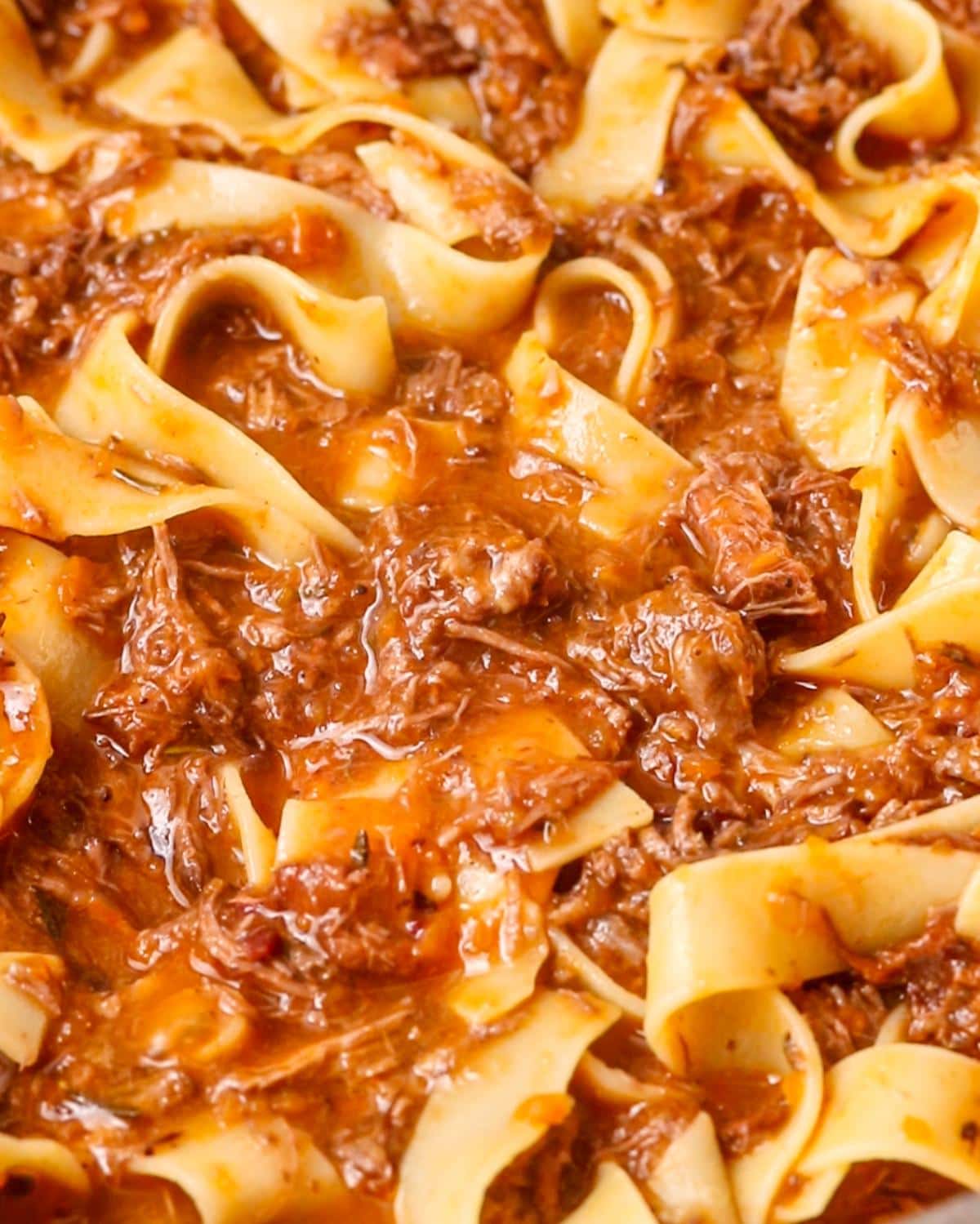 Pappardelle tossed with slow cooked beef ragu in a large skillet.