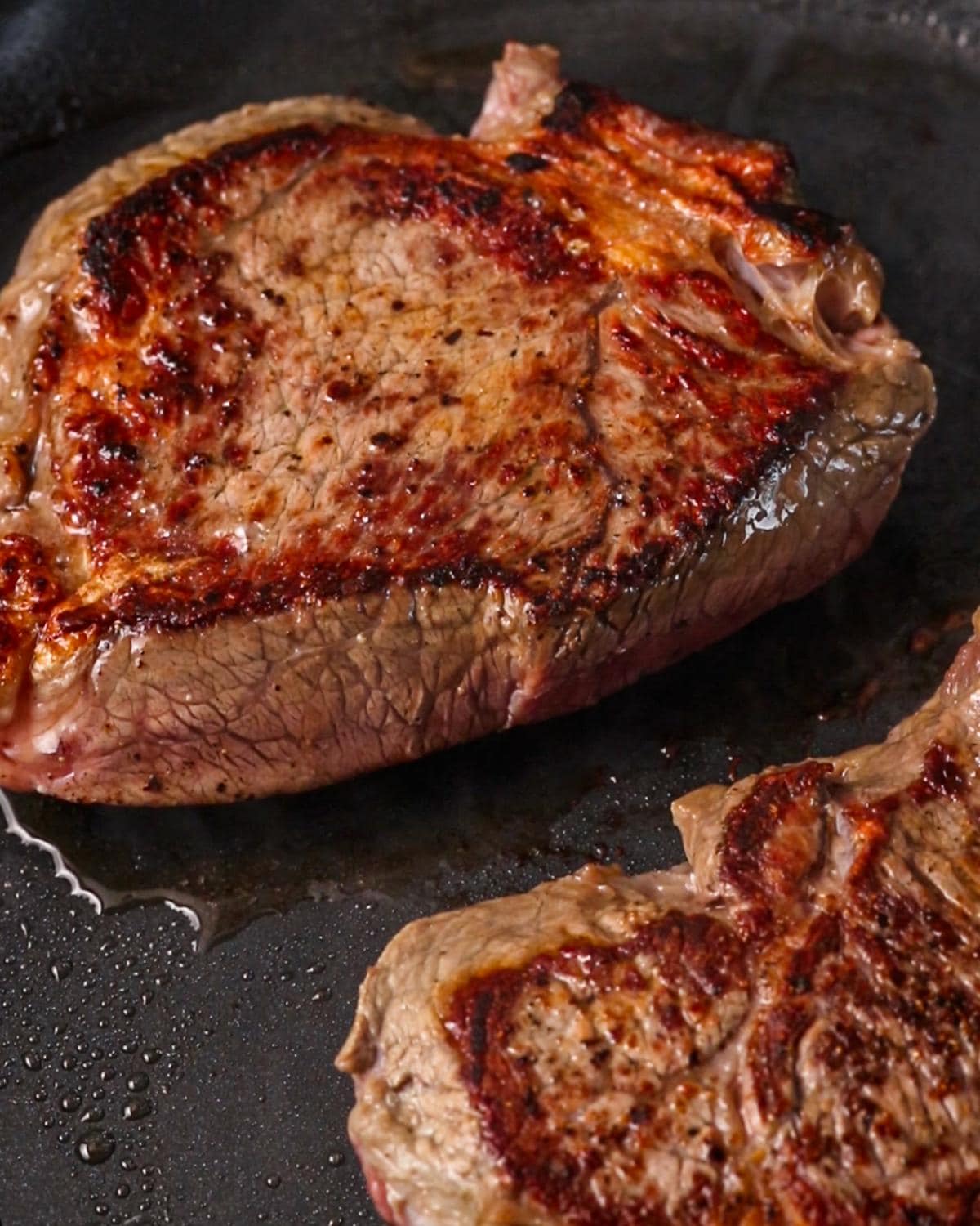 Beef chuck pieces browned in a skillet.