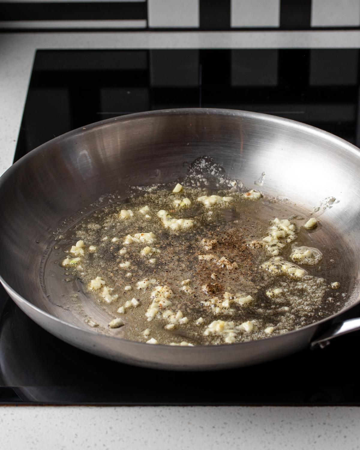 Butter, finely minced garlic and black pepper cooking in a skillet.